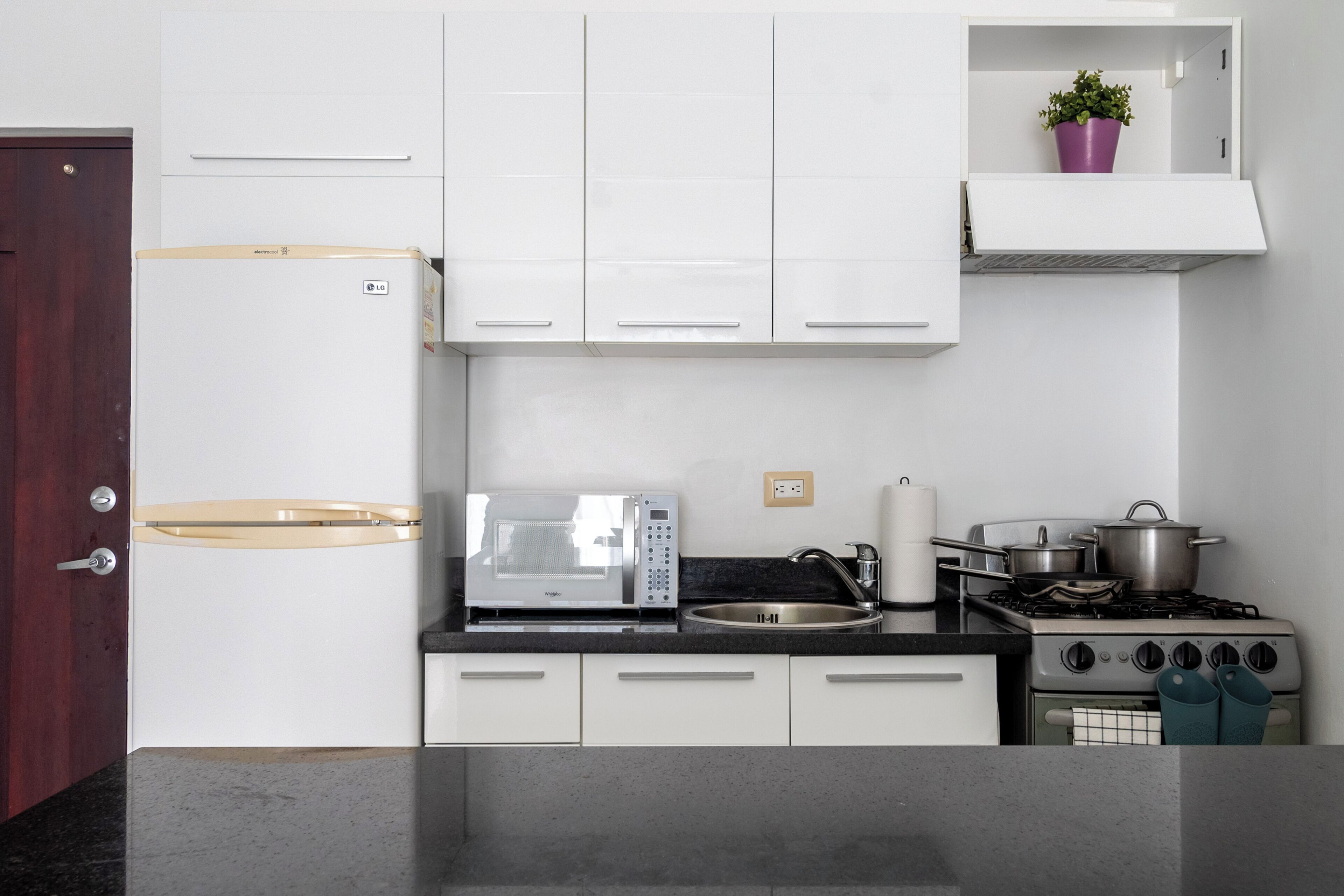 A modern kitchen with white cabinets, a microwave, a stove, and a sink.