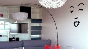 A modern dining area with a white table, clear chairs, and a unique spherical light fixture. - Apartment La Rochelle Magnifique Vue sur Mer (La Rochelle)
