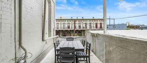 A rooftop terrace with a table and chairs, overlooking a row of colorful buildings.