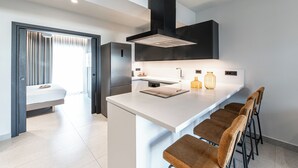 A modern kitchen with a central island, bar stools, and a built-in stove. - Porta Suites (Heraklion)