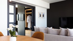 A modern living room with a grey sofa, a wooden dining table, and a white orchid vase. - Porta Suites (Heraklion)