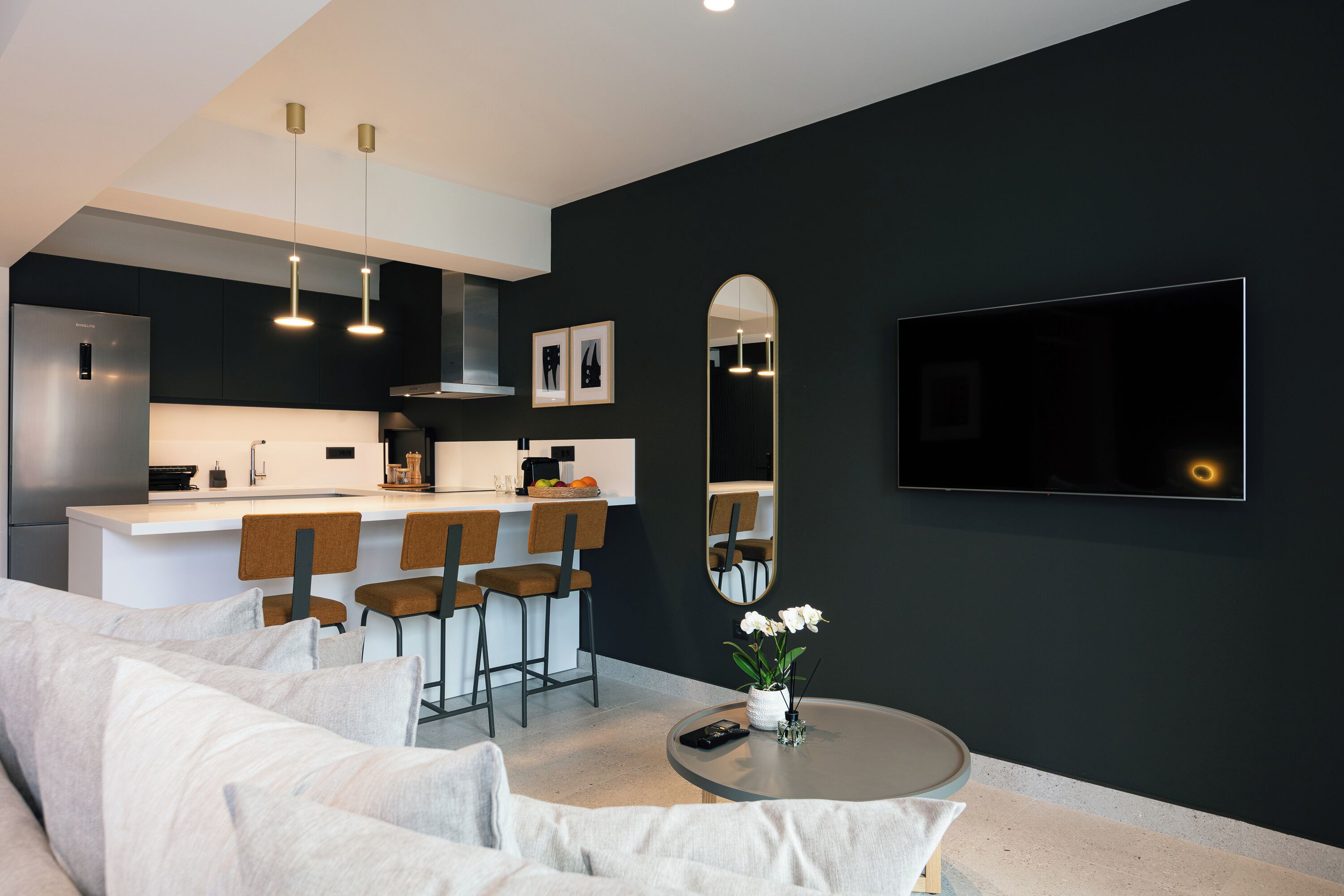 A modern living room with a sofa, a coffee table, and a TV mounted on the wall.