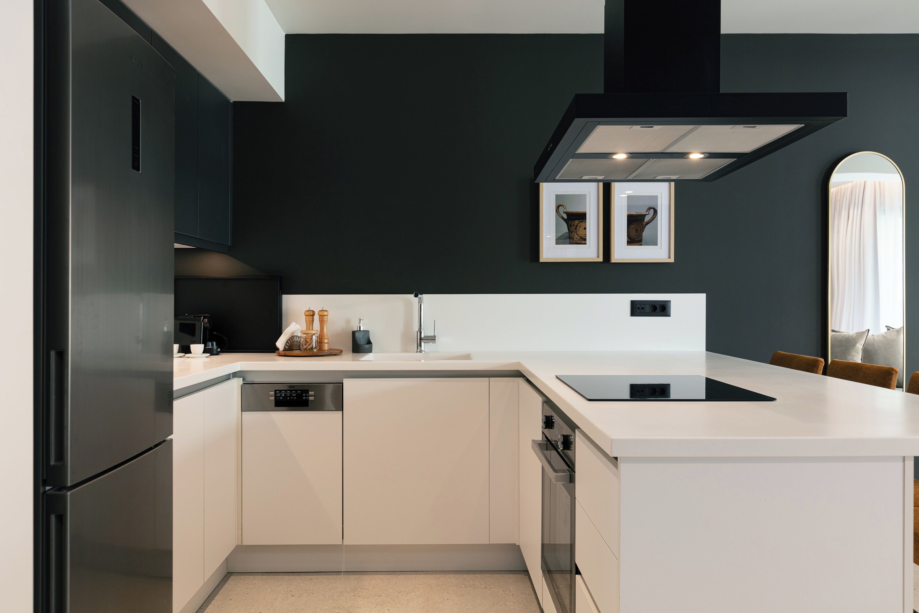 A modern kitchen with a built-in dishwasher, a stainless steel refrigerator, and a sleek black range hood.