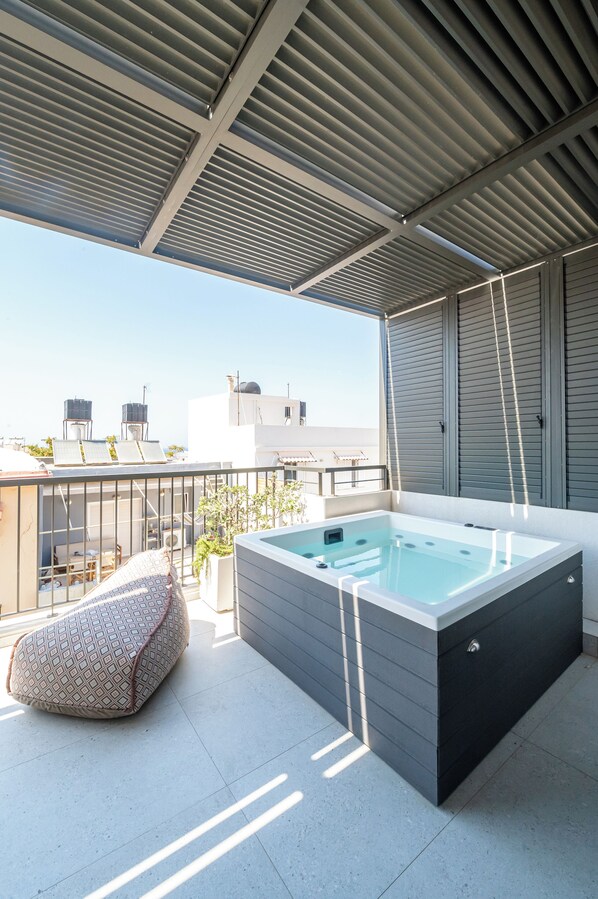 A rooftop terrace with a hot tub, seating area, and a view of the cityscape. - Porta Suites (Heraklion)