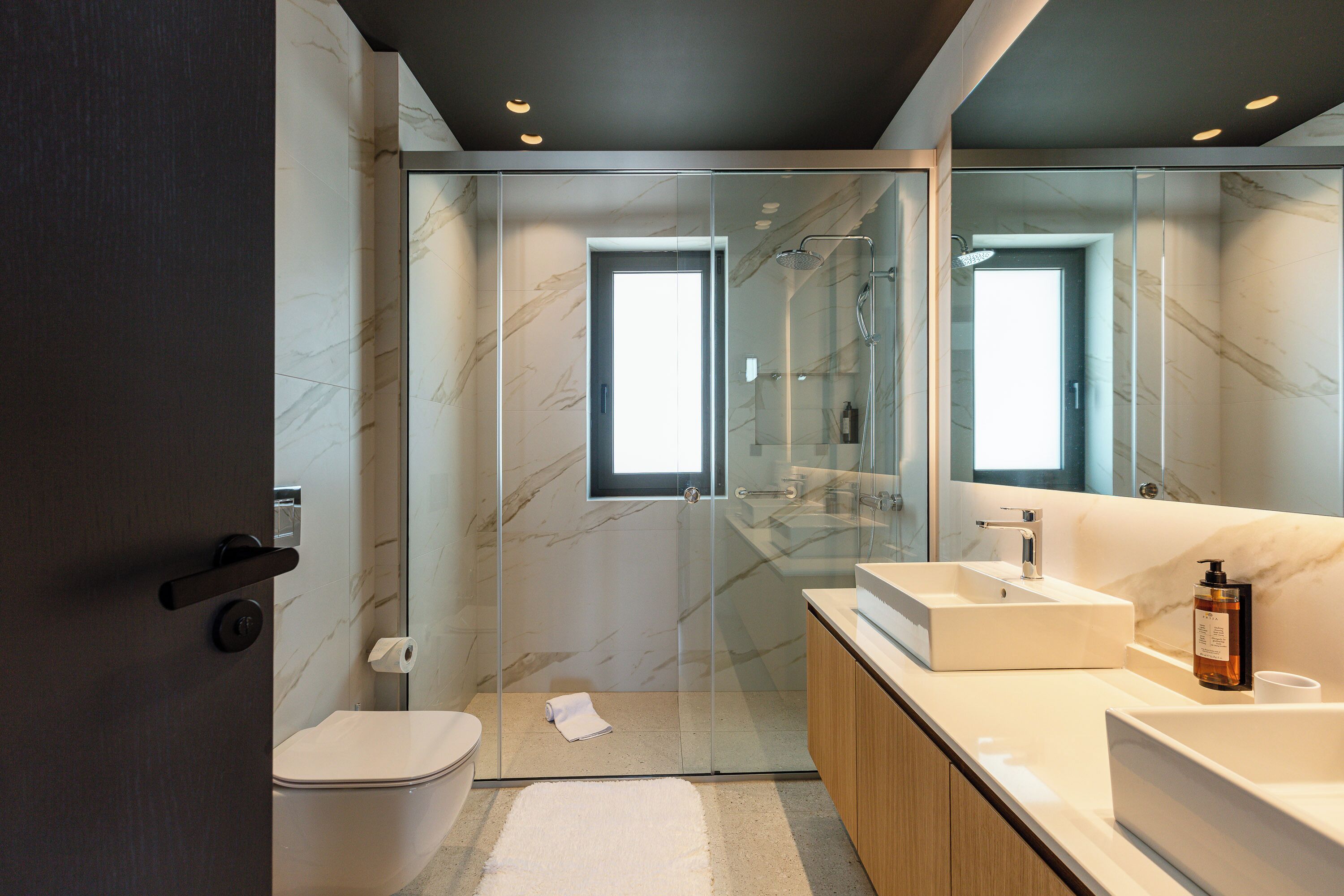 Une salle de bain moderne avec une douche à parois de verre, un lavabo blanc et un grand miroir.