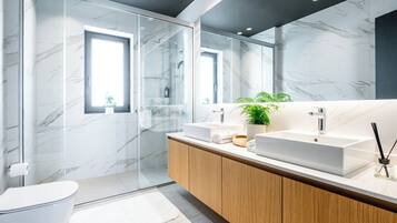 A modern bathroom with a glass shower enclosure, a white sink, and a wooden vanity.