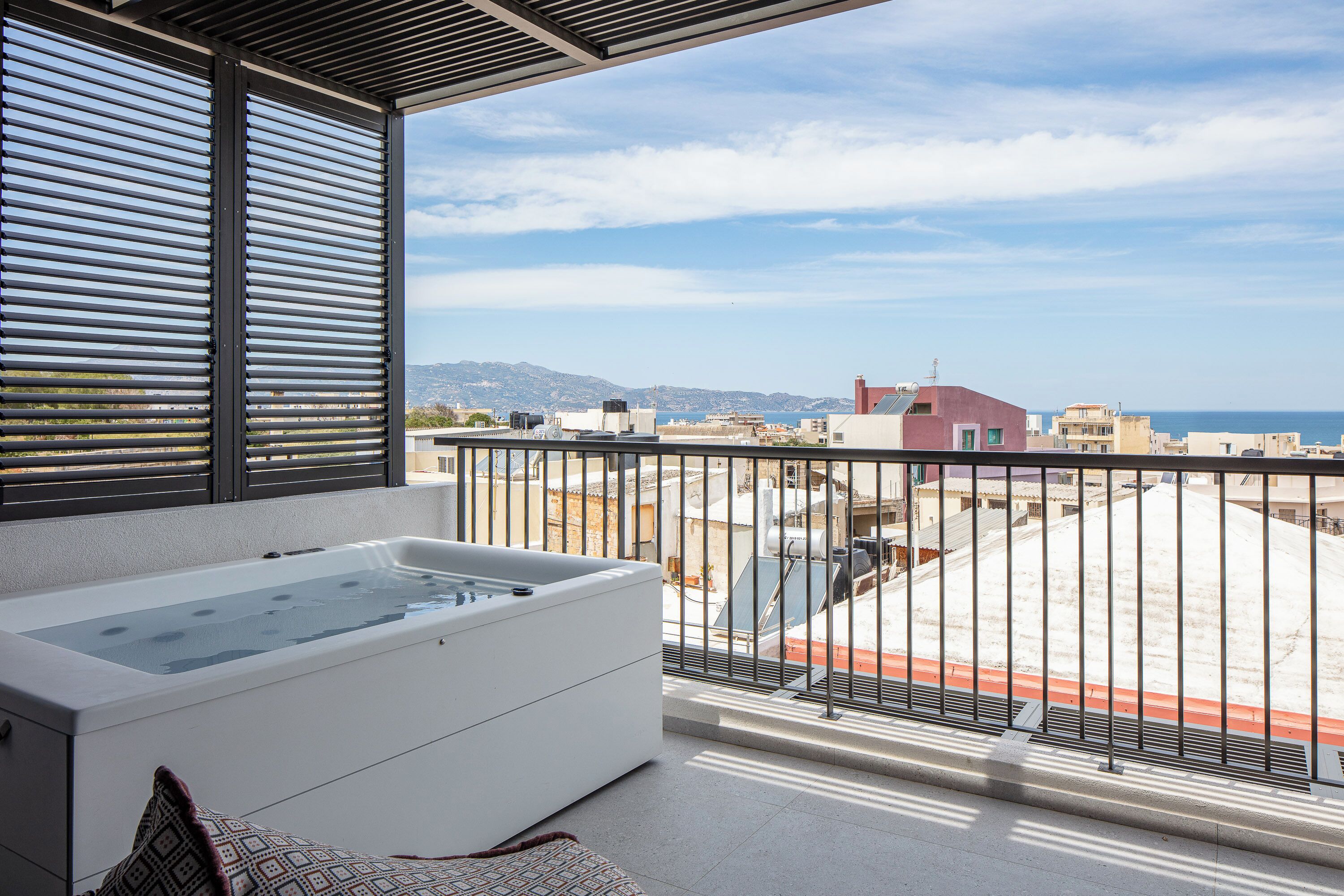 Un balcone con idromassaggio, vista sul mare e edifici sullo sfondo.