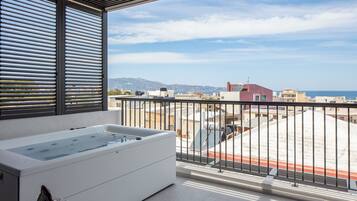 Un balcone con idromassaggio, vista sul mare e edifici sullo sfondo.