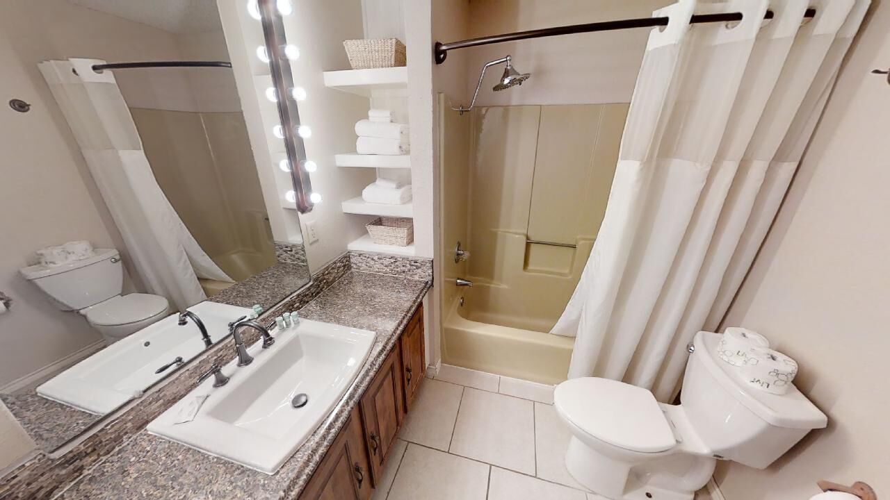 A bathroom with a double sink, a shower, and a toilet.