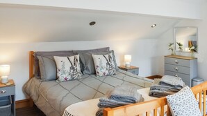 A bedroom with a bed, nightstands, a dresser, and a crib. - 3 bedroom accommodation in Caerarfon (Caerarfon)