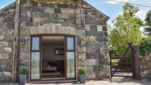 A stone building with a wooden door and a small porch area. - 3 bedroom accommodation in Caerarfon (Caerarfon)