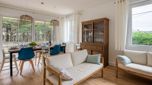 Un soggiorno moderno con un divano, un tavolo da pranzo, sedie e un armadietto in legno.