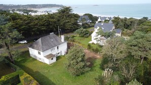Una casa bianca con tetto grigio, immersa nel verde e con vista sul mare.