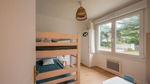 Una stanza con un letto a castello, un tavolo e una finestra che si affaccia sul verde.