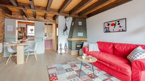 Un salón acogedor con un sofá rojo, una mesa de comedor de madera y una chimenea.
