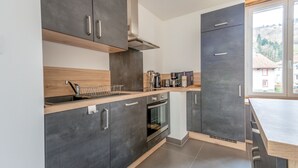 A modern kitchen with grey cabinets, a wooden countertop, and a built-in oven. - Ouréa - duplex avec balcon (La Bresse)