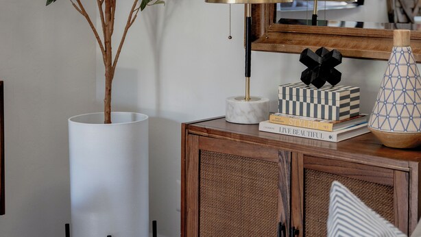 A room with a wooden sideboard, a tall white vase, a floor lamp, a small potted plant, and a mirror on the wall. - Peaceful modern and close to everything (Gainesville)