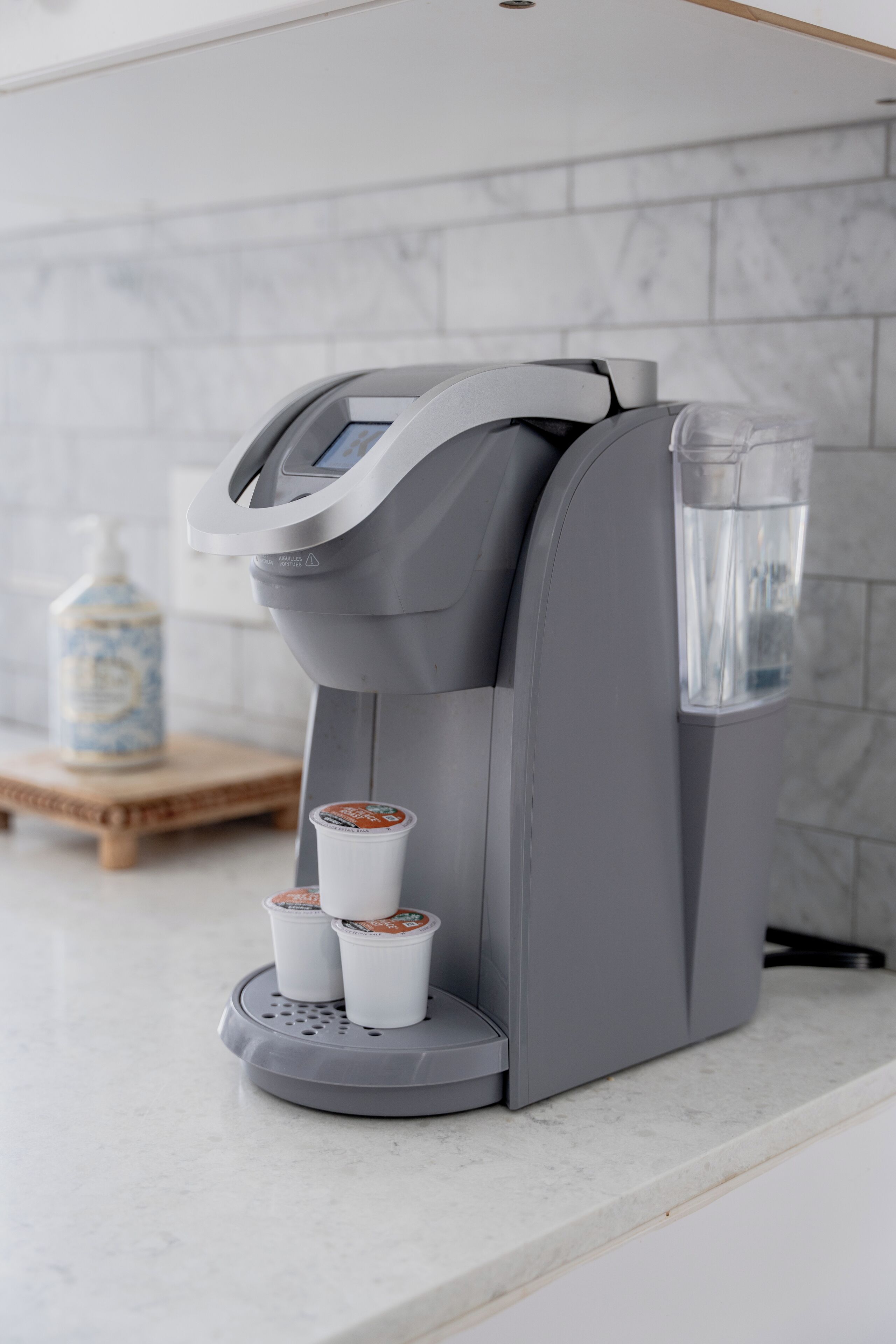A coffee machine with a water reservoir and two coffee pods on a countertop.