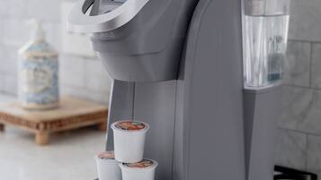 A coffee machine with a water reservoir and two coffee pods on a countertop.