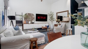 A modern living room with a sofa, armchairs, a coffee table, a TV, and a ceiling fan. - Peaceful modern and close to everything (Gainesville)