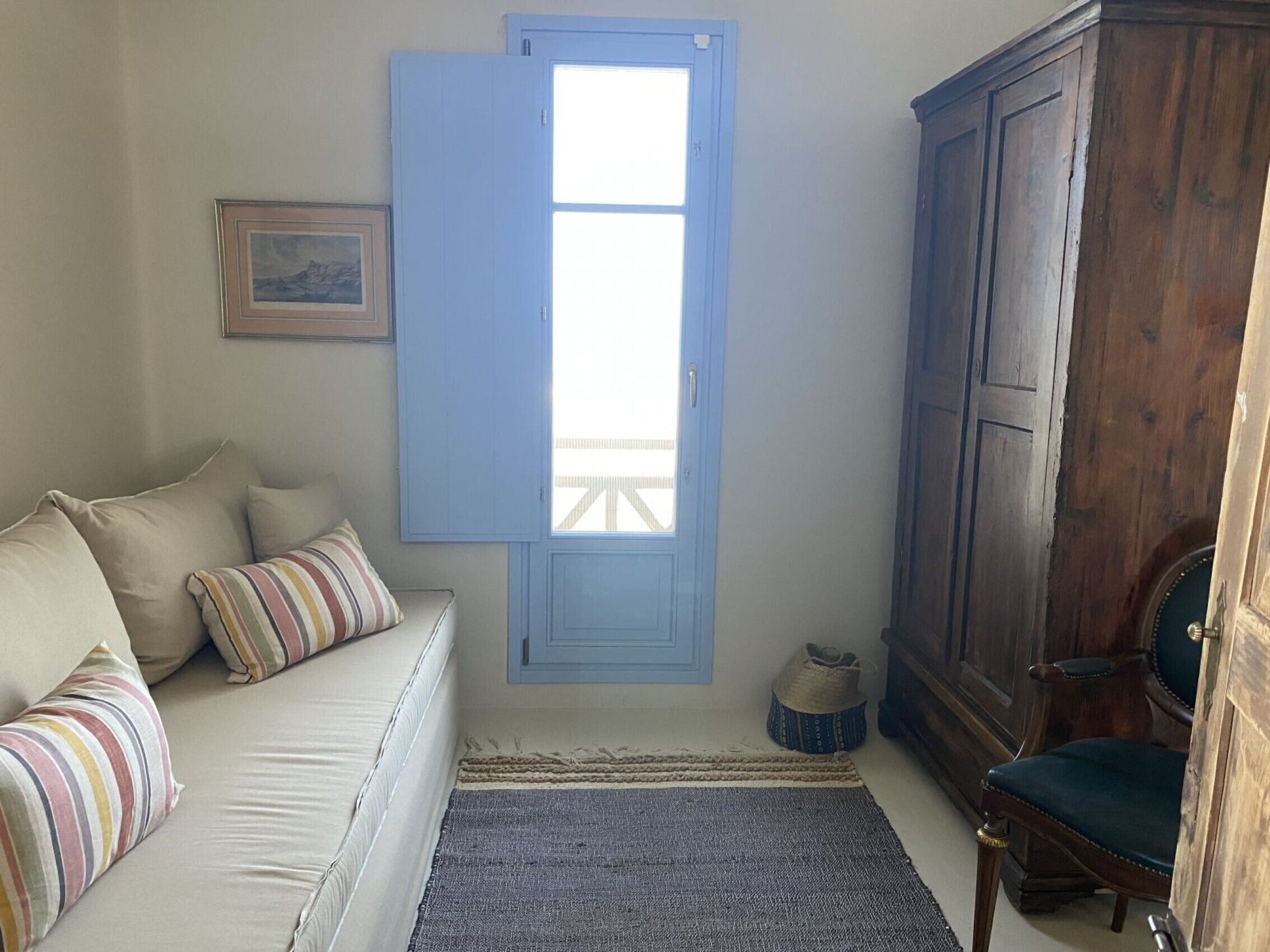 Ein Zimmer mit einem Bett, einer blauen Tür, einem Holzschrank und einem Sessel.