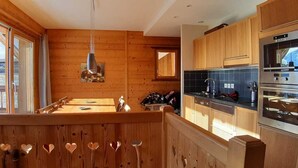 Un interno in legno con angolo cottura dotato di elettrodomestici moderni, un tavolo da pranzo e vista attraverso un'ampia finestra.