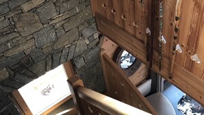 Una scala in legno con un muro di pietra e una finestra che si affaccia sull'esterno.