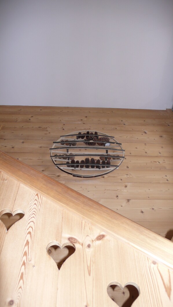 A wooden floor with a circular arrangement of pine cones and a heart-shaped cutout. - Typical chalet, south-facing terrace, breathtaking VIEW of the Tarentaise Valley (Montvalezan)