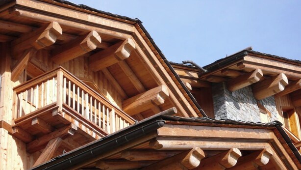 Un edificio in legno con un balcone e un muro in pietra.