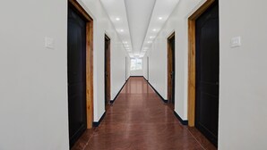 Un pasillo largo y estrecho con puertas de madera oscura a ambos lados y un suelo brillante y reflectante.