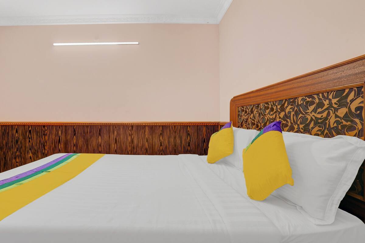 A hotel room with a bed, wooden headboard, and a decorative wall panel.
