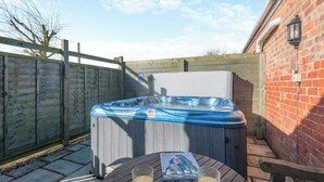 Ein Whirlpool mit Holztisch und zwei Gläsern Orangensaft in einem Hinterhof.