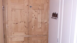 Ein Holzkleiderschrank mit Herzförmigem Ausschnitt, eine weiße Tür mit Griff und ein kleines dekoratives Element an der Wand.