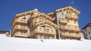 Ein mehrstöckiges Holzgebäude mit Balkonen, vermutlich ein Hotel, vor dem sich ein strahlend blauer Himmel erstreckt.