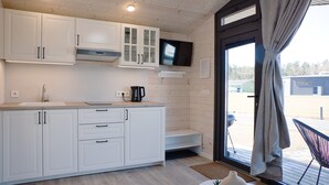 Een moderne keuken met witte kastjes, een inbouwoven en een flatscreen televisie boven de aanrecht.