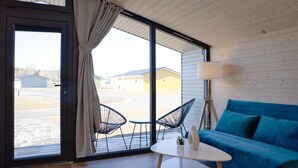 Een kamer met een blauwe bank, een witte tafeltje en twee zwarte stoelen.