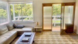 A living room with a sofa, coffee table, and a sliding glass door leading to a balcony. - Classic Beach House Sandy Point (Sandy Point)
