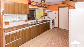 A kitchen with wooden cabinets, a white stove, and a sink. - Classic Beach House Sandy Point (Sandy Point)