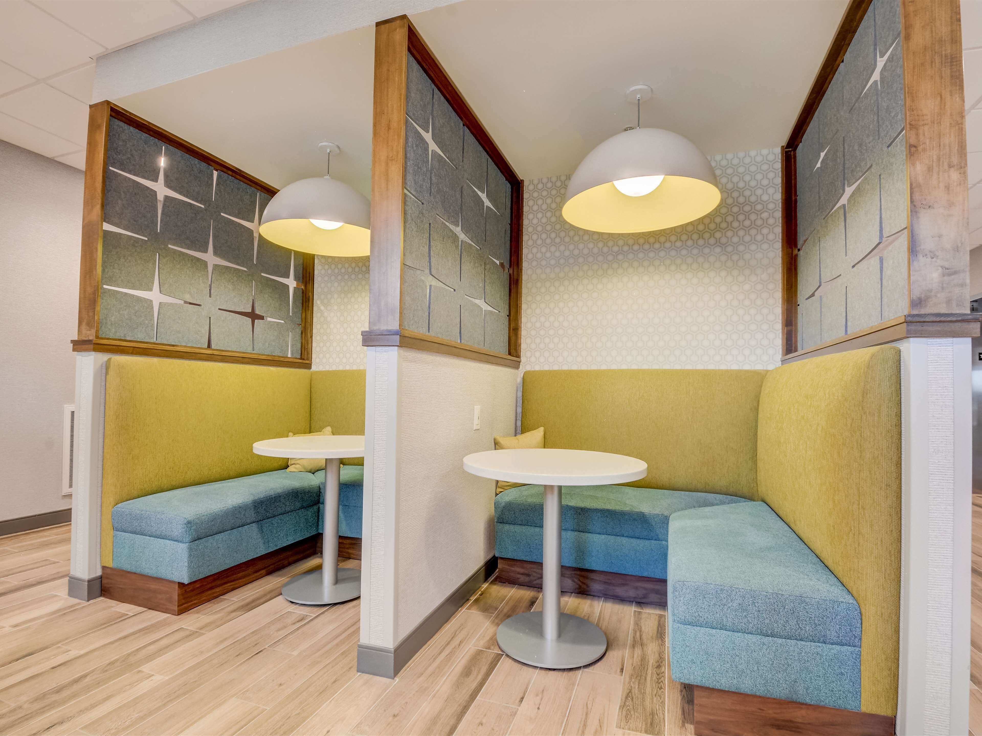 A corner seating area with two round tables and cushioned seating.