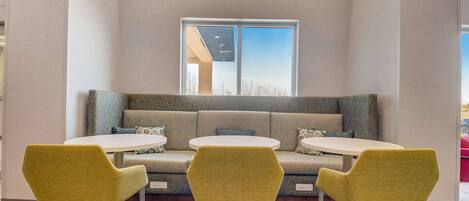 A seating area with a sofa and three round tables, each with a single chair.