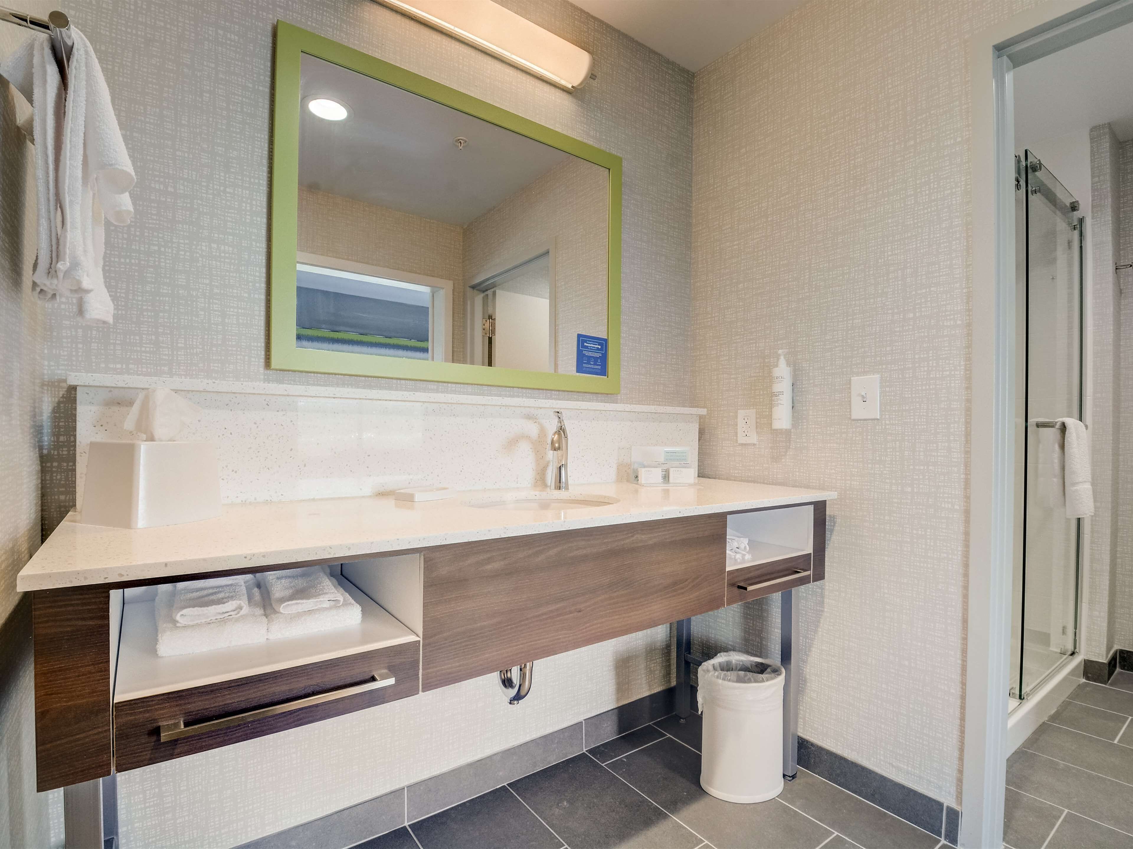 A modern bathroom with a large mirror, a sink, and a shower area.