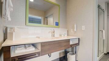 A modern bathroom with a large mirror, a sink, and a shower area.