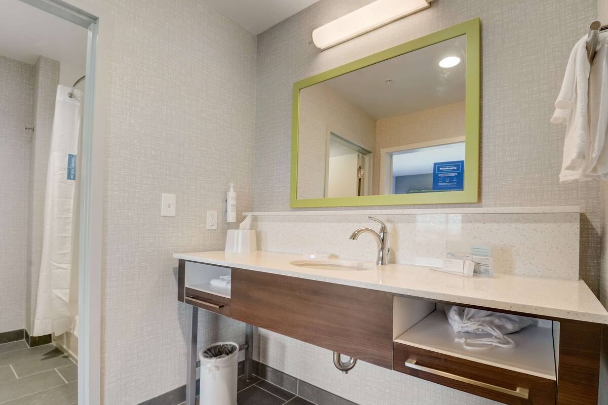 A modern bathroom with a large mirror, a sink, and a vanity with a towel rack.