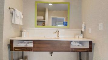 A modern bathroom with a wooden vanity, a mirror with a green frame, and a towel rack.
