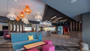 A modern lobby with a blue sofa, pink ottomans, and unique pendant lights. - Tru By Hilton Fayetteville Fort Bragg (Fayetteville)