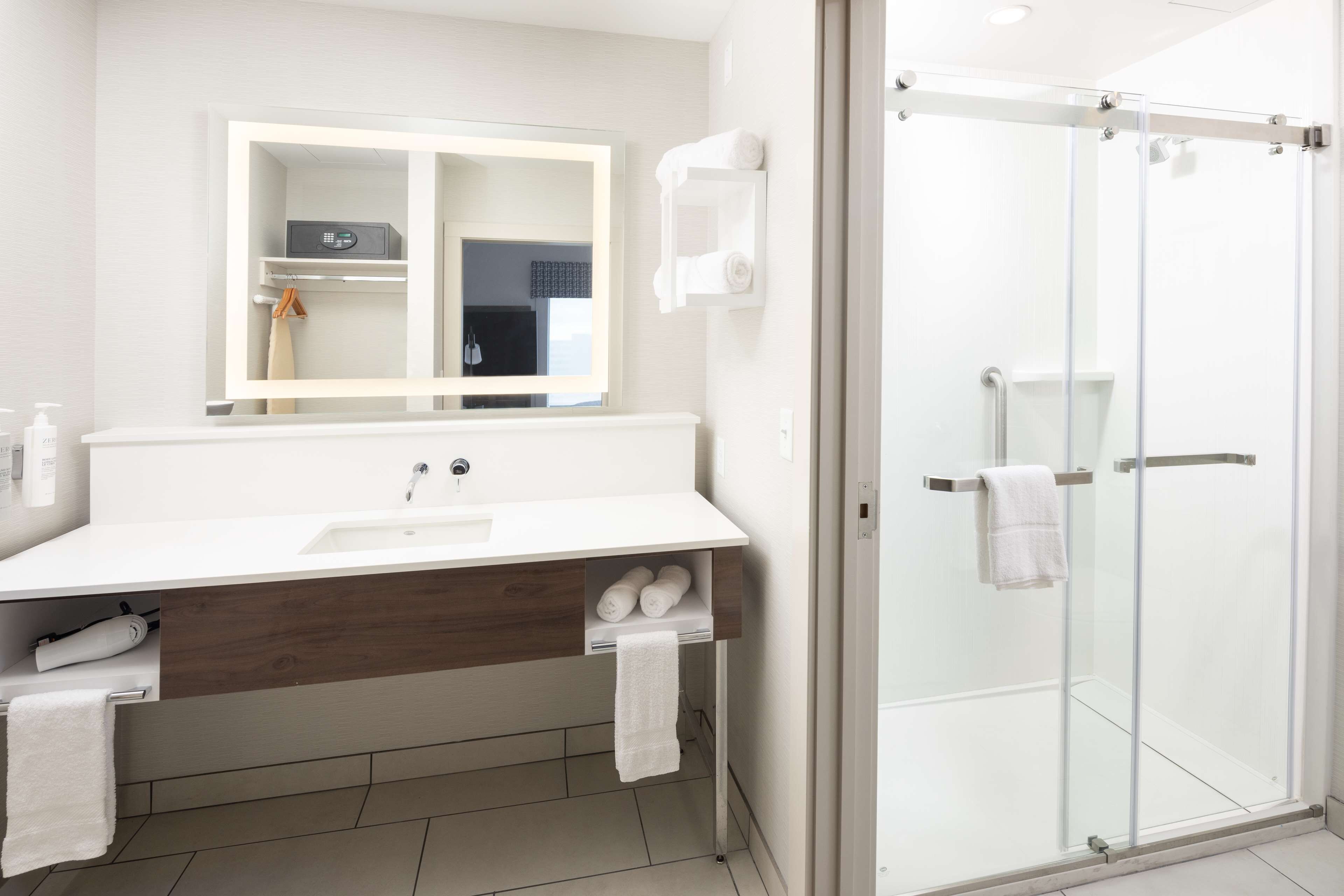 A modern bathroom with a white sink, mirror, and glass shower enclosure.