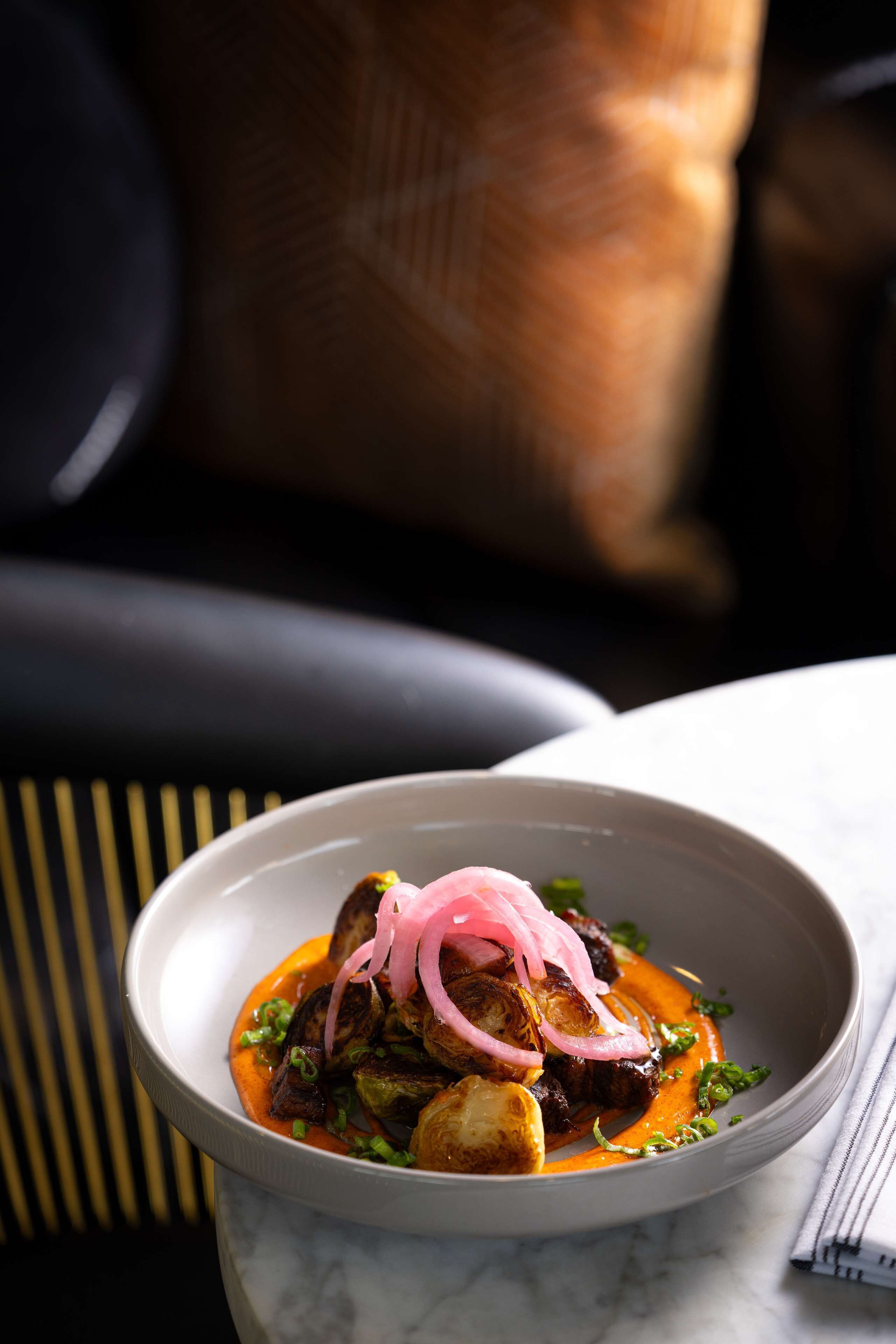 A bowl of food with a white interior and a dark background.