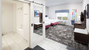 A modern hotel room with a shower, a bed with two pillows, a desk, and a large window with a city view. - Hampton Inn & Suites Rochester Downtown (Rochester)