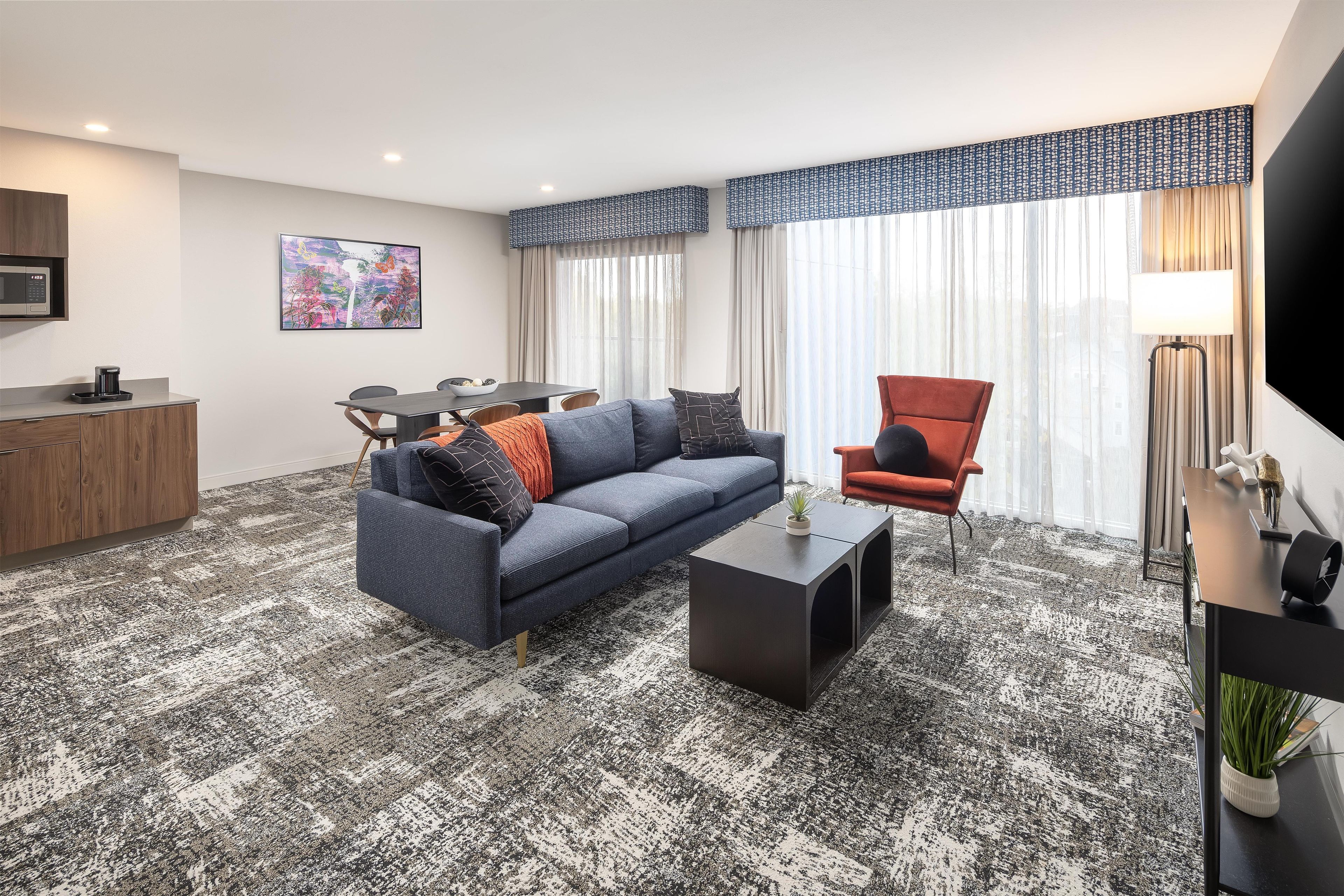 Een moderne zithoek met een bank, fauteuil, salontafel, en een eethoek met een tafel en stoelen.