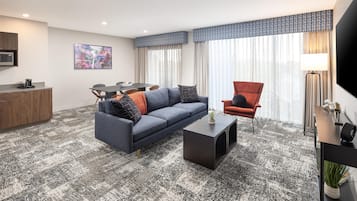 Een moderne zithoek met een bank, fauteuil, salontafel, en een eethoek met een tafel en stoelen.